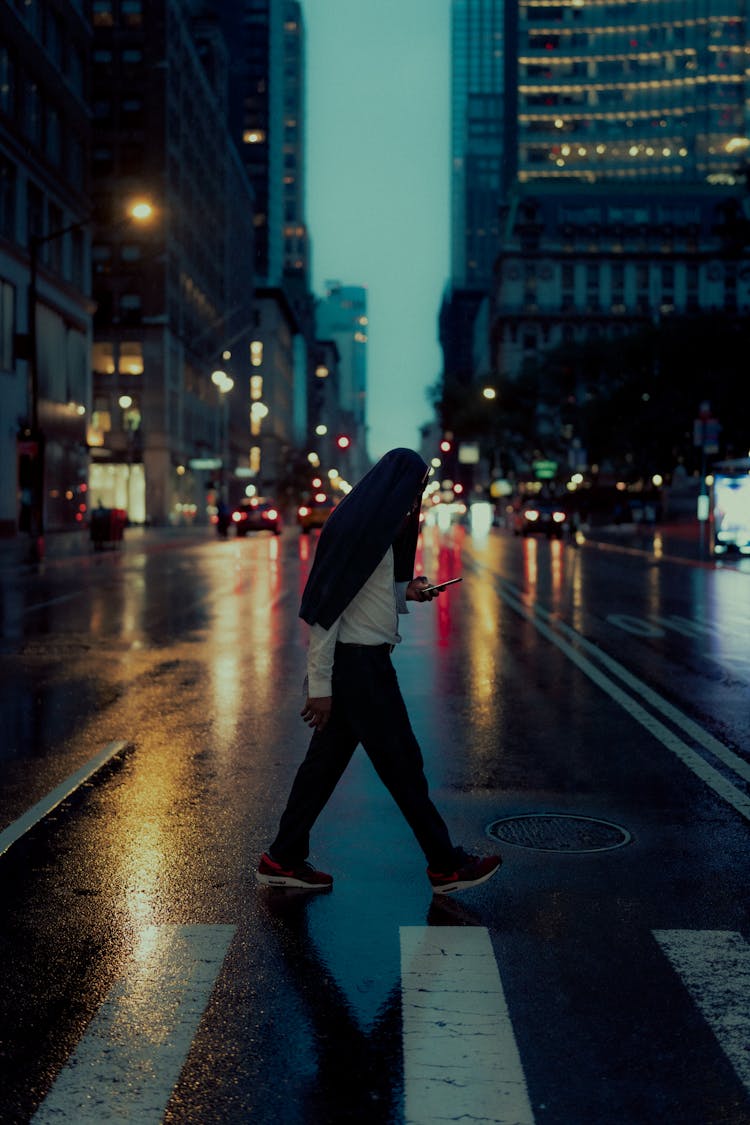 A Person Walking On The Street While Using Mobile Phone