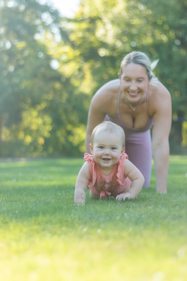 A Baby Girl Crawling On The Lawn With Mom