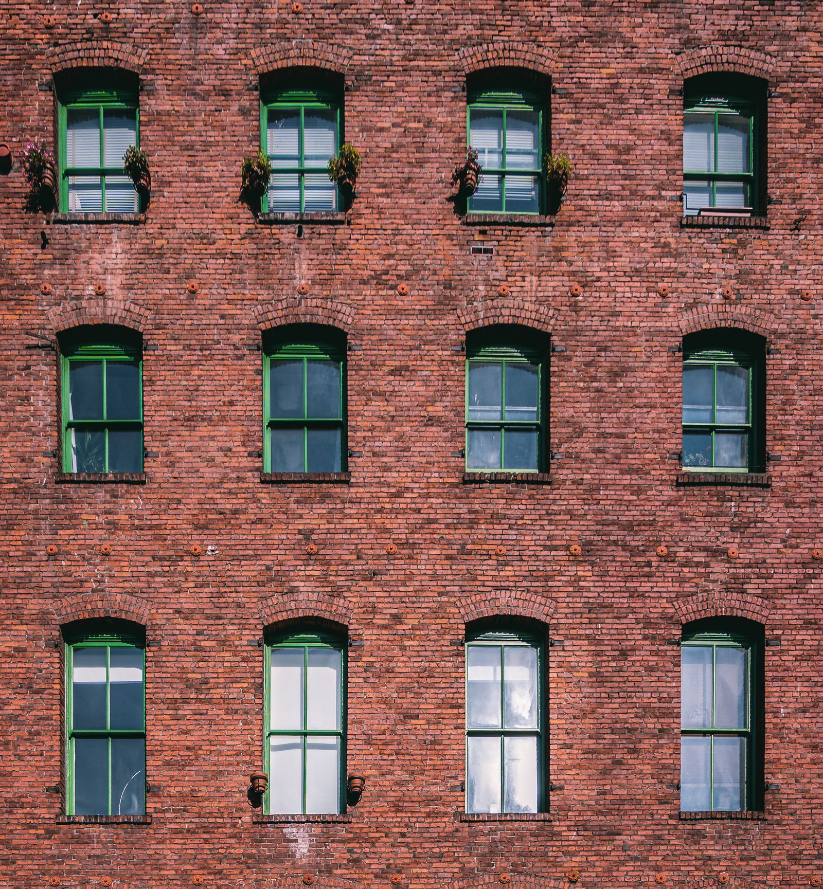 Façade d’un immeuble ancien en brique rouge, avec des rangées de fenêtres à encadrement clair.