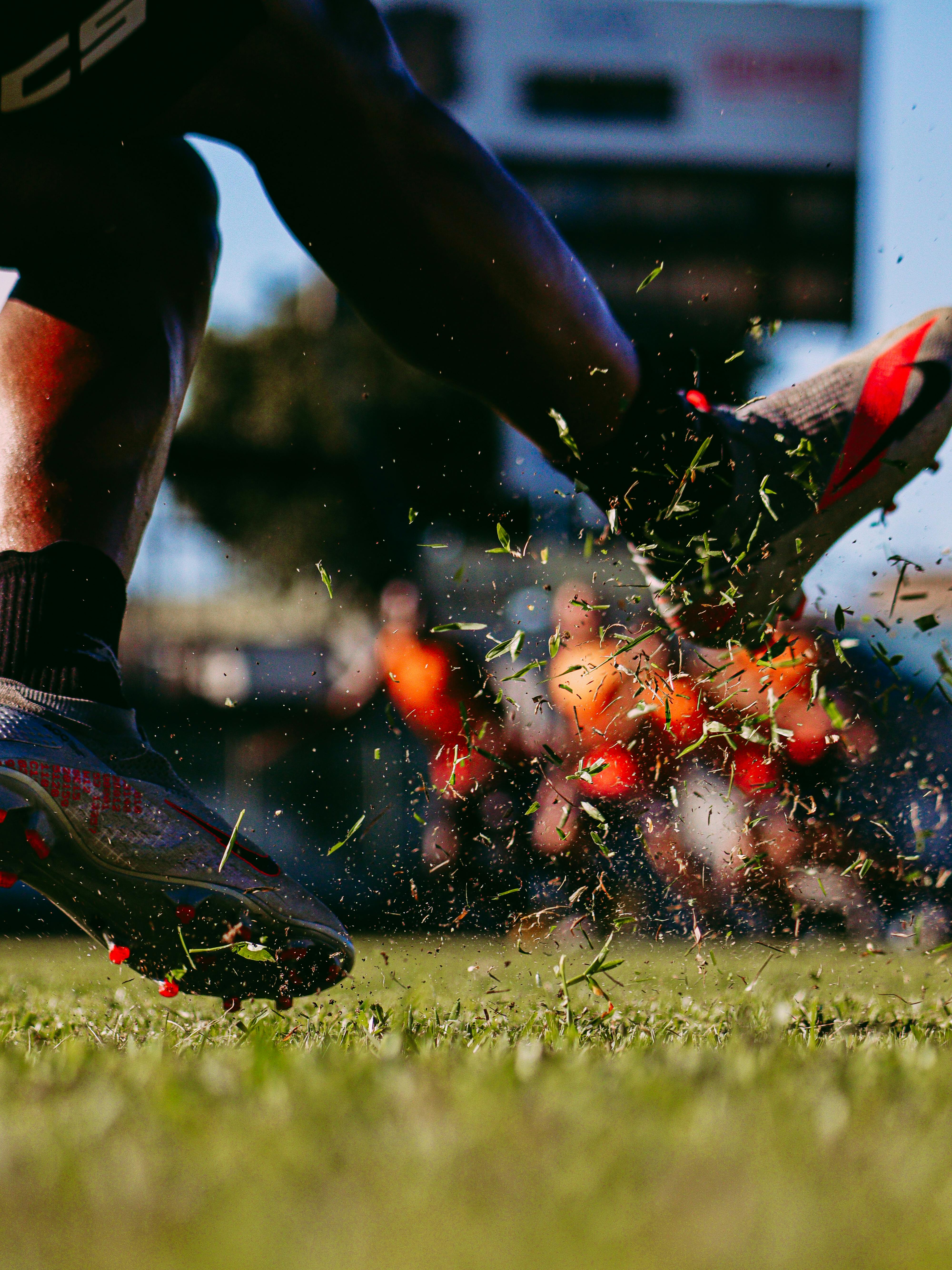 Dynamic close-up of a soccer kick creating a spray of grass during a game.