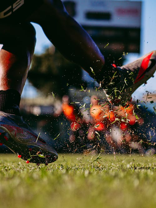 Free A Man Wearing Cleats Kicking the Ball on Field Stock Photo
