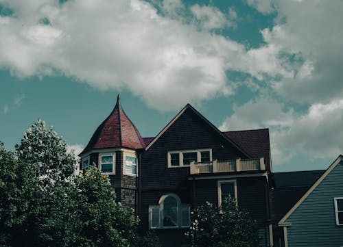 A Low Angle Shot of a House Near the Green Trees Under the White Clouds