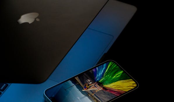 A vibrant smartphone screen displaying colorful imagery next to a laptop in low light.