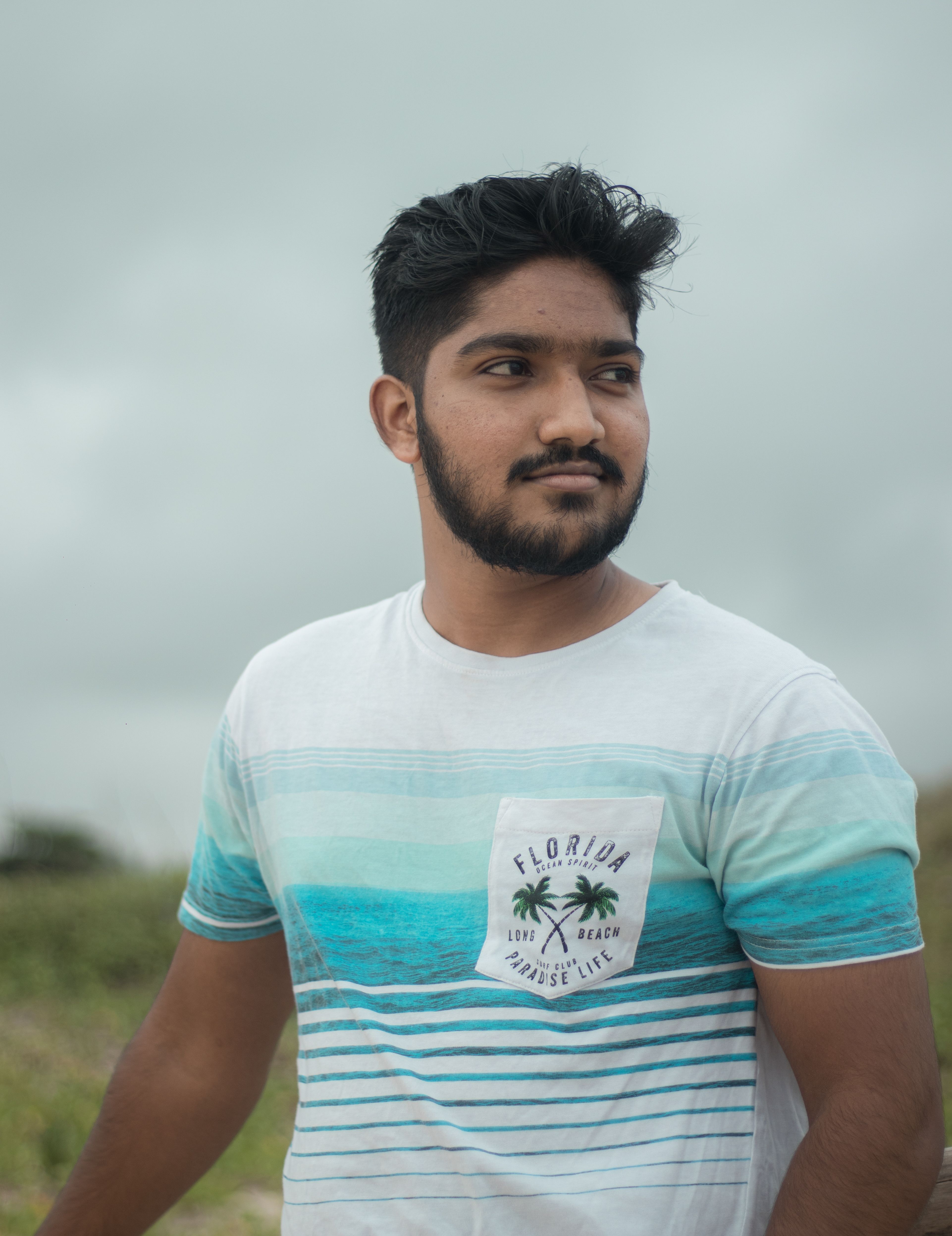 Relaxed young man in a striped t-shirt posing outdoors with a calm expression.