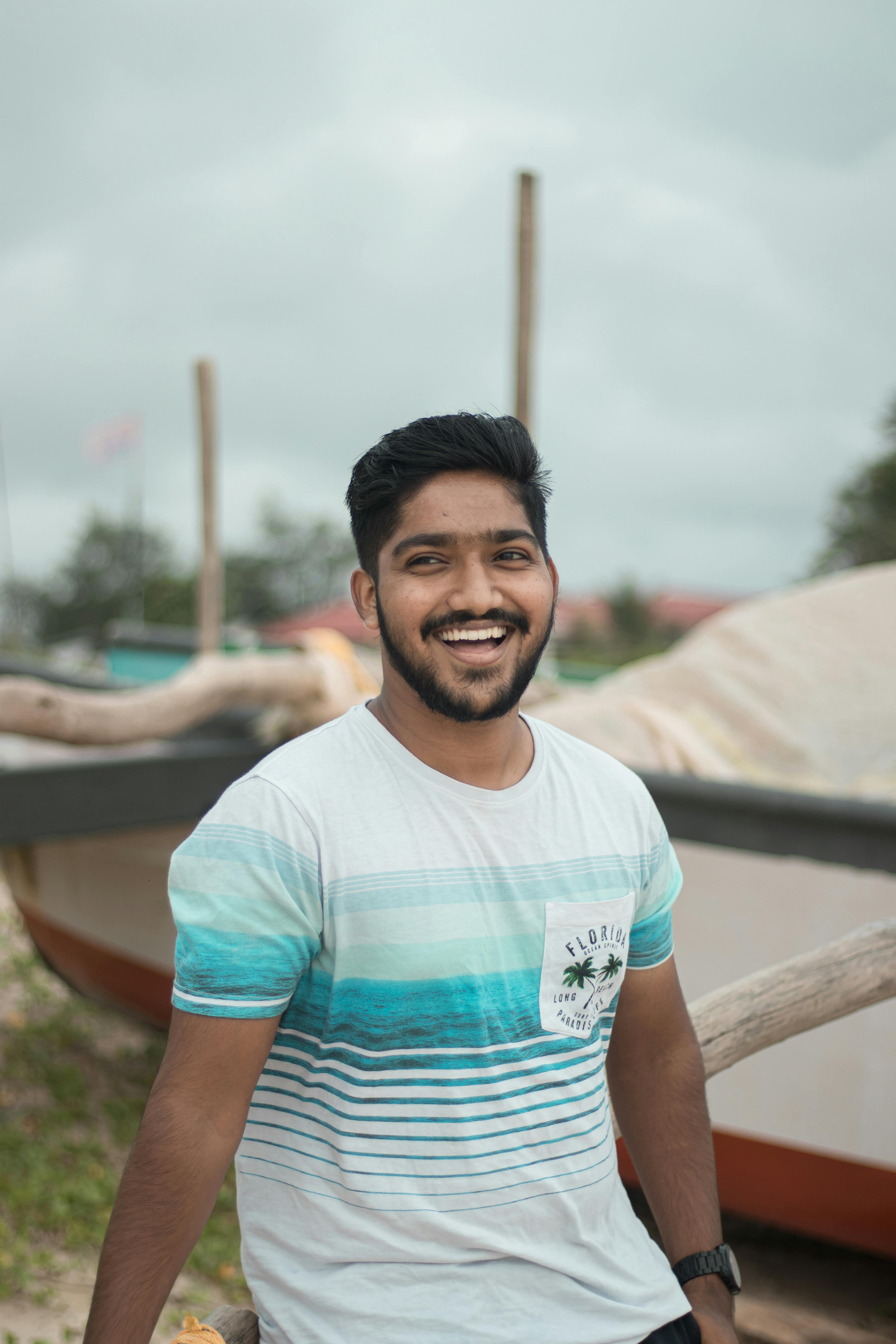 Happy young man with a beard enjoying the outdoors at a seaside location.