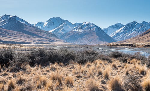 A Brown Grass Field Near the Snow Covered Mountains