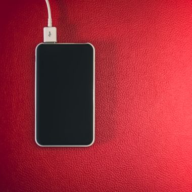 Smartphone resting on a red leather surface, photo by Steve A Johnson on Pexels