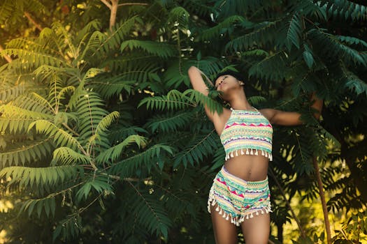 Woman posing in colorful summer attire among lush green foliage, showcasing fashion outdoors.