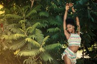 一个快乐的年轻女子穿着五颜六色的服装，站在户外郁郁葱葱的绿树中