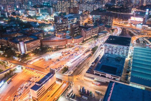 A vibrant aerial view of Kowloon's bustling cityscape at night, showcasing traffic and buildings.