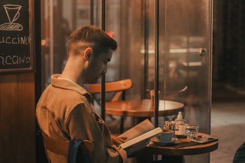 Free Man in Velvet Jacket Reading Book and Sitting by the Table Stock Photo