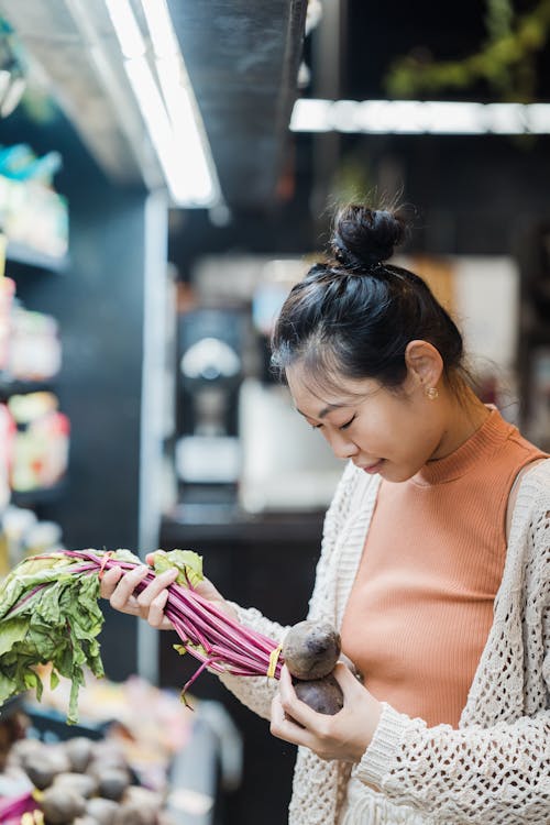 A Woman Holding a Beetroot in a Supermarket