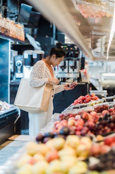Asian woman choosing fresh fruits in a vibrant indoor supermarket setting.