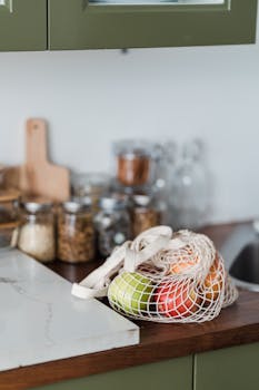 Fresh fruits in a mesh bag on a kitchen counter, promoting sustainability and zero waste lifestyle.
