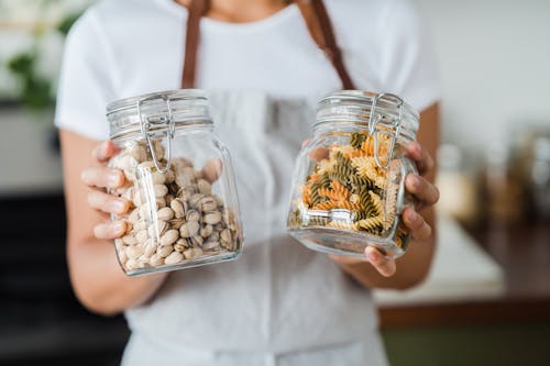 Close-Up Shot of a Person Holding Two Glass Jars