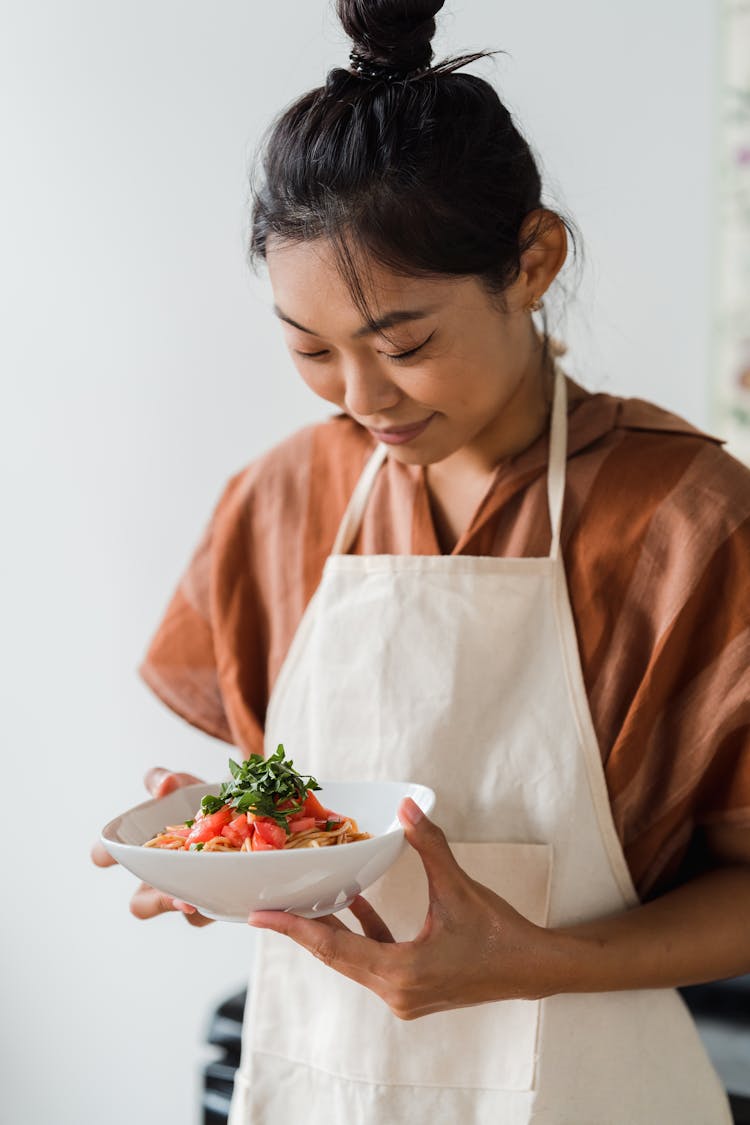 A Woman Holding A Bowl Of Delicious Pasta