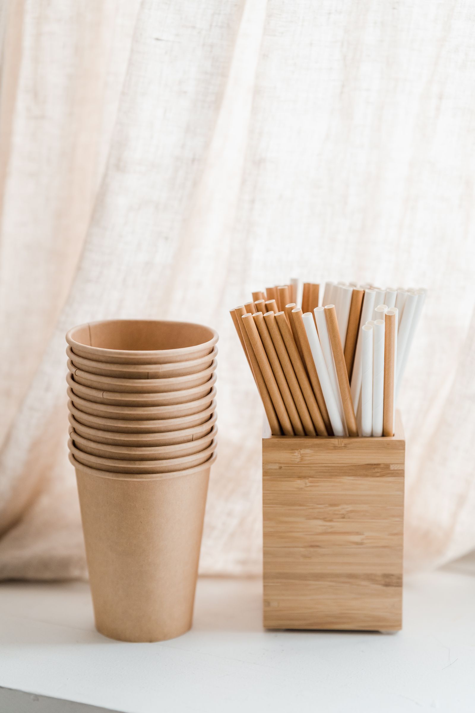Paper cups beside natural drinking straws in a wooden box