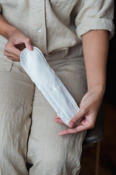 Close-up of a woman holding a sanitary pad, emphasizing menstrual hygiene.