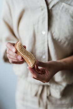 Detailed view of hands holding a wooden body brush for personal hygiene, promoting wellness.