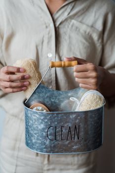 Close-up of hands holding a tin bucket with hygiene products, promoting cleanliness.