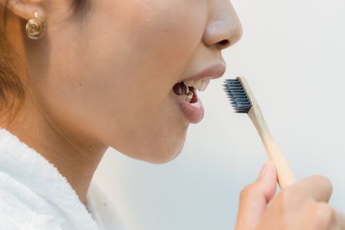 Free Close-up of a woman practicing oral hygiene with an eco-friendly bamboo toothbrush. Stock Photo