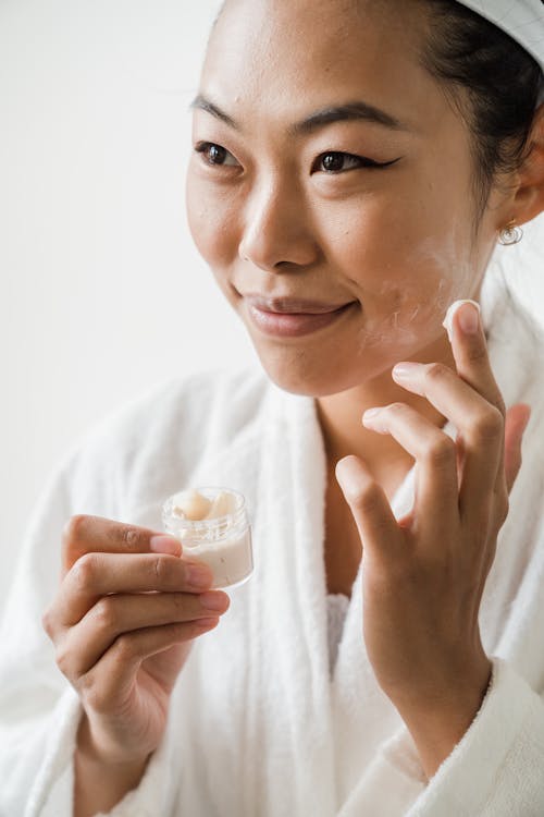 Smiling Woman Applying Facial Cream on Her Face