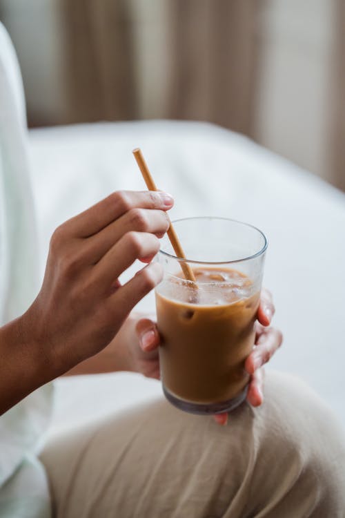 Close-Up Shot of a Person Holding a Glass of Iced Coffee