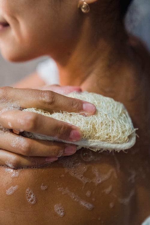 Free Close-up of a woman using a loofah sponge for exfoliating during a shower. Stock Photo