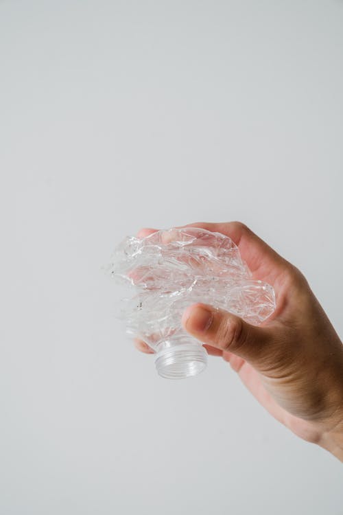 Close-Up Shot of a Person Holding a Crumpled Plastic Bottle