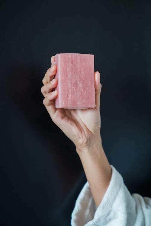 Close-Up Photo of a Person Holding a Pink Bar Soap