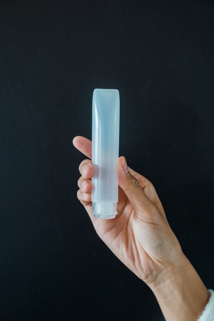 Close-Up Photo Of A Person Holding A Plastic Cylinder Tube