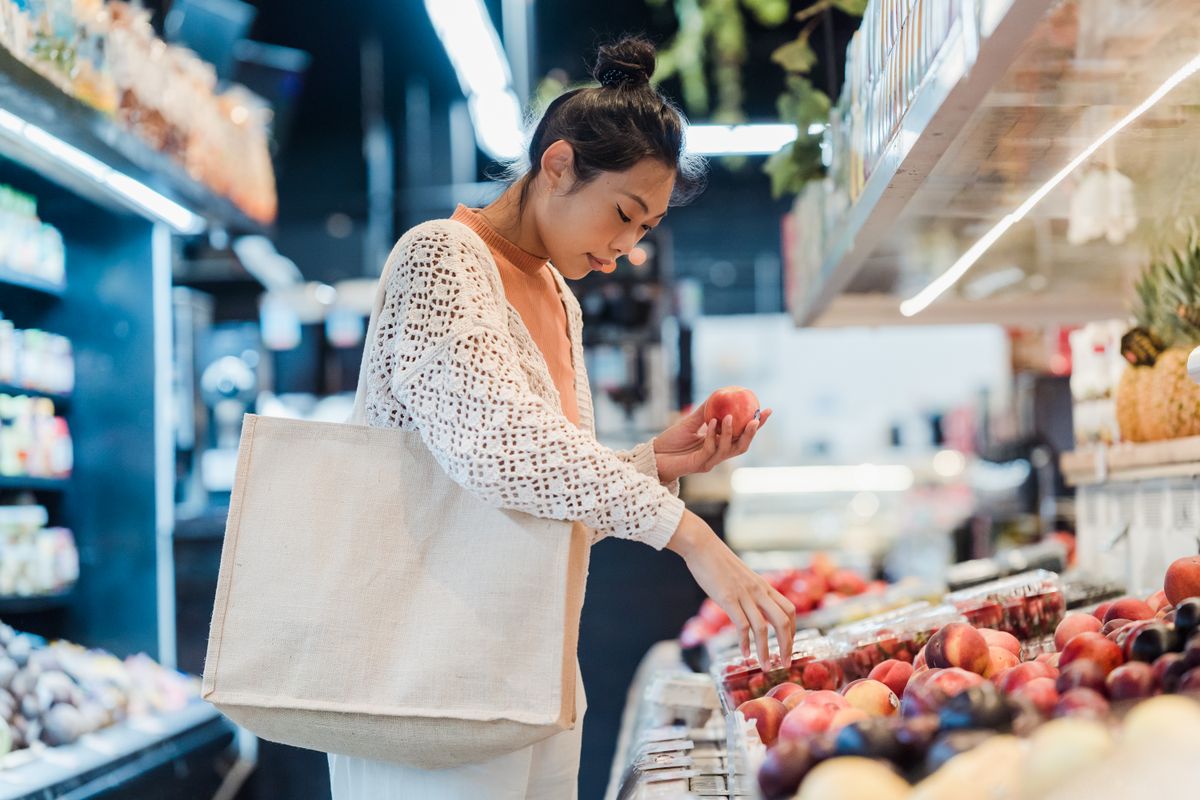 Shopper carrying a reusable tote bag in a grocery store