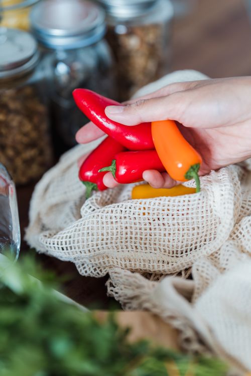 Free Hand holding colorful red and orange bell peppers in a kitchen setting. Stock Photo