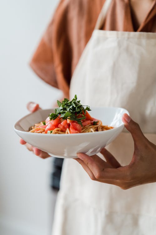Close-Up Photo of a Person Holding a Bowl of Delicious Pasta