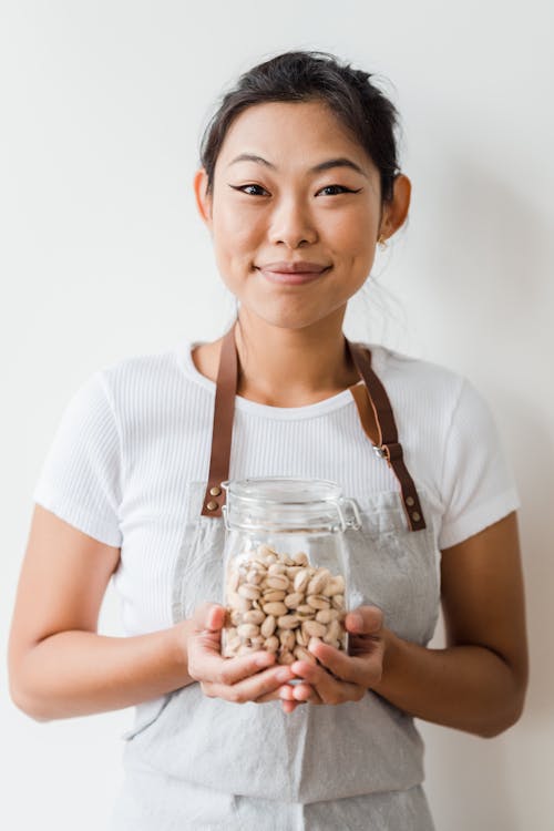 Free Smiling Woman Holding a Jar of Pistachio Nuts Stock Photo