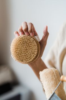 Close-up of a hand holding a natural bristle body brush for personal care.