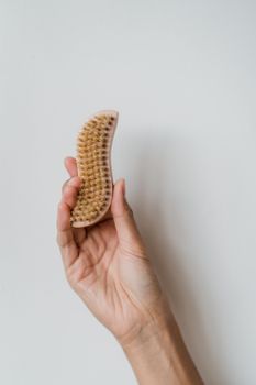 Close-up of a hand holding a natural bristle body brush for personal hygiene and skincare routines.