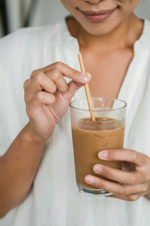 Close-Up Shot of a Person Holding a Glass of Iced Coffee