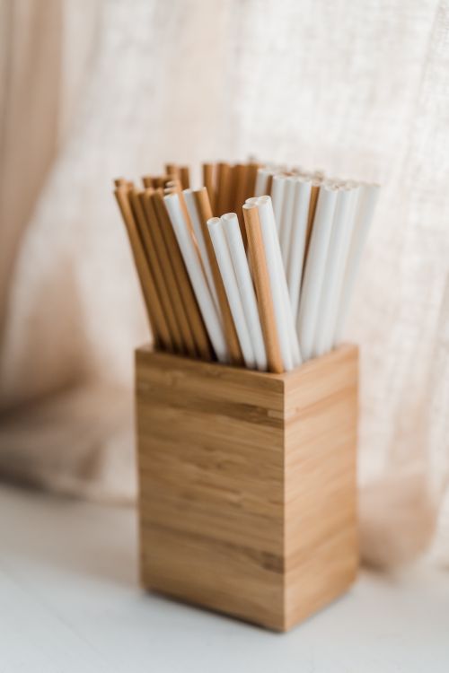 Free Close-up of bamboo and paper drinking straws in a wooden holder, emphasizing eco-friendly alternatives. Stock Photo