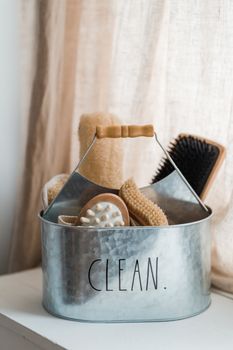 A neatly arranged set of personal care brushes in a metal bucket labeled 'Clean.'