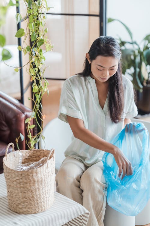 Free Woman Putting Empty Plastic Bottles in a Blue Plastic Bag Stock Photo