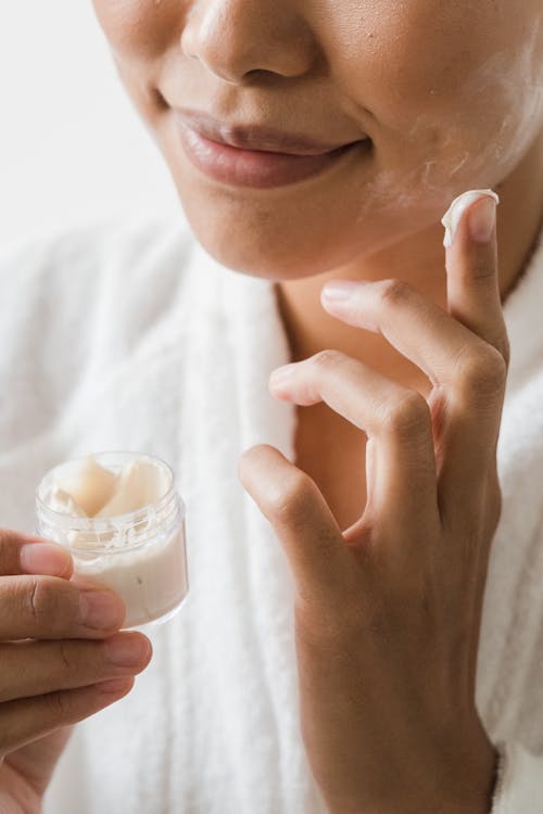 Close-Up Photo of a Person Applying Facial Cream on Her Face