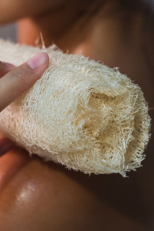 Free Close-up of a hand using a natural loofah sponge for skin exfoliation. Stock Photo