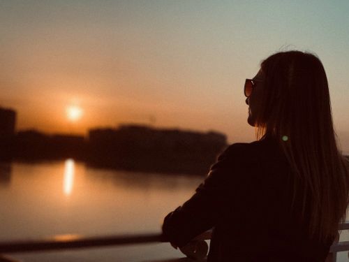 Free A woman in sunglasses enjoys a serene sunset view over the river in Krasnodar, Russia. Stock Photo