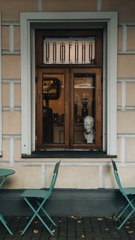 Charming cafe window in Moscow with a bust, chairs, and a classic architectural facade.
