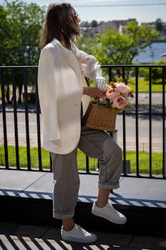 Stylish woman with prosthetic hand holding flowers in a basket, enjoying a sunny day outdoors.