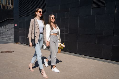Free Fashionable women holding hands, walking outside on a sunny day. Stock Photo