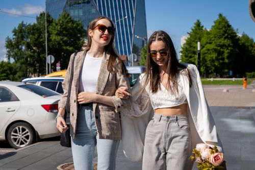 Free Two stylish young women walking together outdoors on a sunny day, showcasing casual fashion and friendship. Stock Photo
