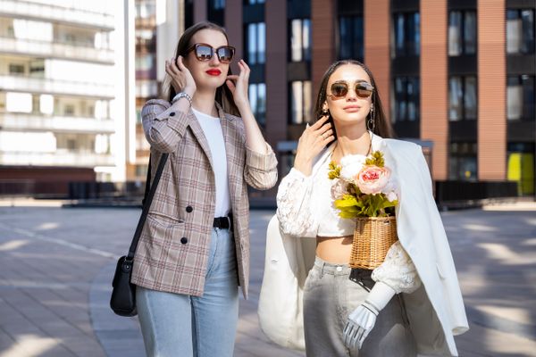 Two people on a bright pavement, one carrying a shoulder bag — photo by Mikhail Nilov on Pexels