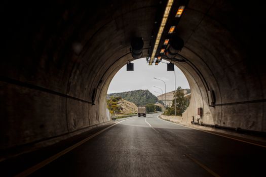 Truck driving through a scenic tunnel on a highway in Cyprus, with mountains in view.